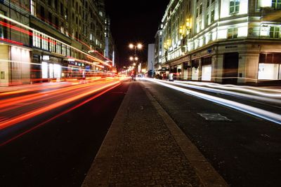 Light trails on road amidst buildings in city at night