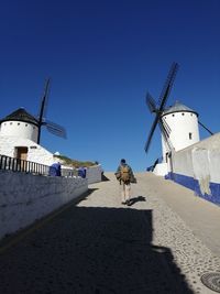 Rear view of man standing amidst traditional windmills on walkway
