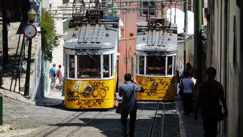 People and cable cars in city during sunny day