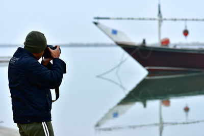 Man photographing while standing against clear sky