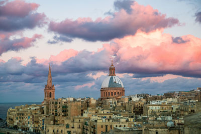 Buildings in city against cloudy sky