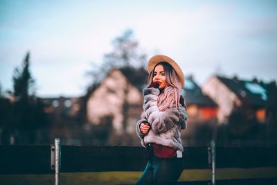 Portrait of woman standing by railing against sky