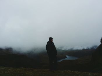 Rear view of young man standing at edge of mountain