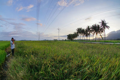 Rear view of person standing on field against sky