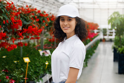 Portrait of a smiling young woman standing against plants