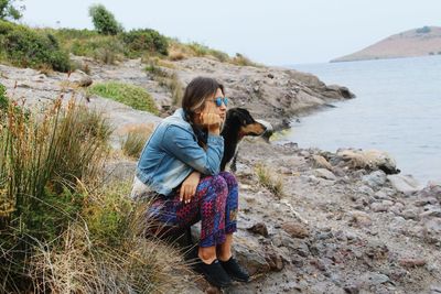 Woman sitting by sea