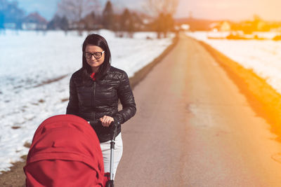 Woman with stroller walking on road 