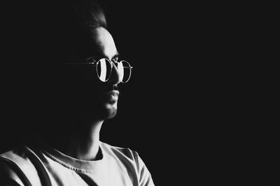 Close-up portrait of boy wearing hat against black background