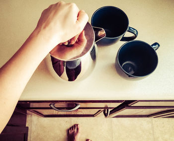 Directly above shot of woman with teapot and cups on table