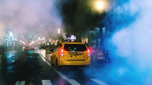 Cars on road against illuminated city at night