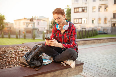 Woman using phone while sitting in city