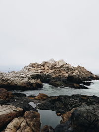 Rocks in sea against clear sky