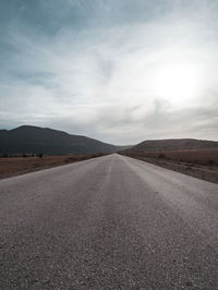 Empty road along landscape against sky