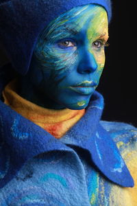 Young woman with painted face against black background