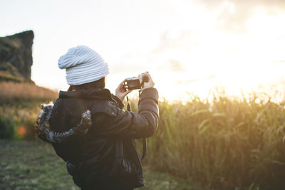 Rear view of woman photographing on field