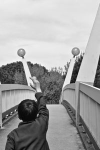 Rear view of boy playing with ball against sky