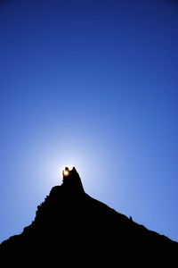 Low angle view of silhouette person on mountain against clear sky