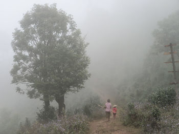 Rear view of women walking on street amidst trees