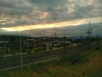 Railroad tracks on field against cloudy sky