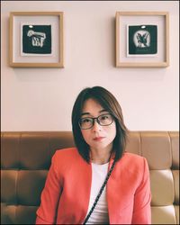 Portrait of beautiful woman sitting against wall