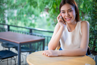 Portrait of a smiling young woman sitting on table