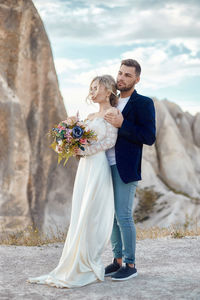 Couple holding umbrella while standing by flower