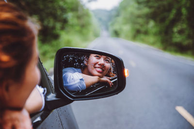 Portrait of woman photographing car on road