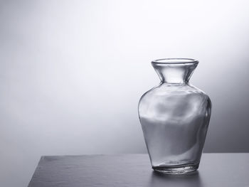 Close-up of glass bottle on table against white background