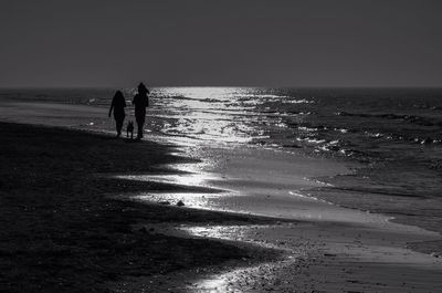 People walking on beach against sky