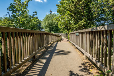 Footbridge amidst trees against sky