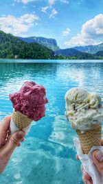 Hand holding ice cream cone in front of water lake bled slovenia hands with ice cream