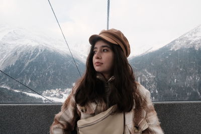 Portrait of young woman on snowcapped mountains during winter