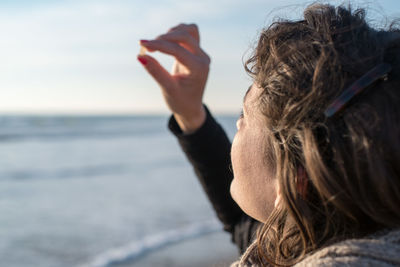 Side view of woman standing at beach against sky