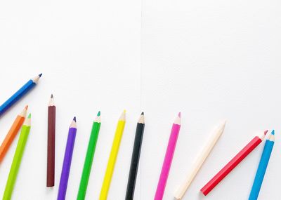 High angle view of colored pencils against white background