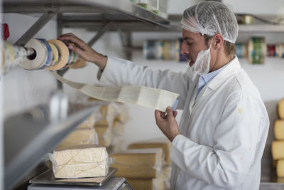 Cheese factory worker weighing packaged cheese