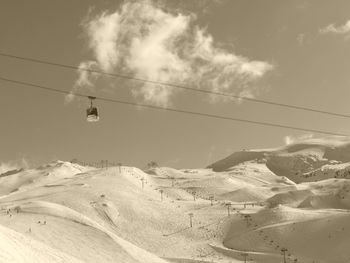 Overhead cable car over snowcapped mountains against sky