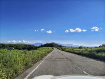 Empty road amidst field against sky