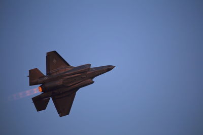 Low angle view of airplane flying against clear blue sky