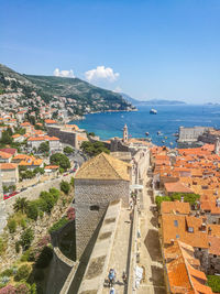 High angle view of city by sea against blue sky