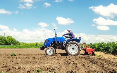 Farmer drives a tractor with a milling machine. loosens, grind and mix soil on plantation field.