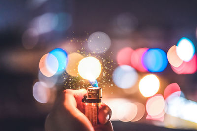 Close-up of hand holding illuminated candles