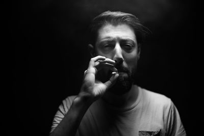 Mature man smoking cigarette against black background