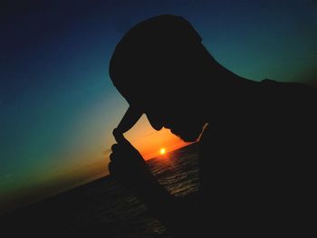 Close-up of silhouette man against sea at sunset