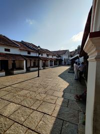 Footpath by buildings in city against sky