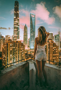 Rear view of woman standing by buildings against sky