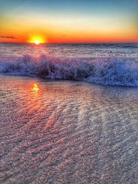 Close-up of wet beach against sky during sunset