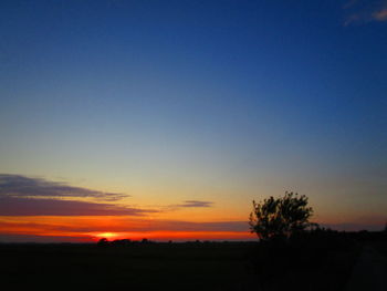 Scenic view of silhouette field against clear sky during sunset