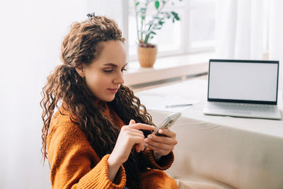 Side view of young woman using digital tablet while sitting at home