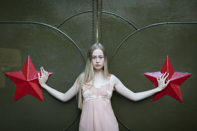 Portrait of beautiful woman standing by closed metal gate