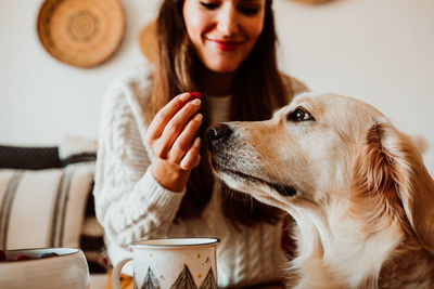 Midsection of woman feeding dog at home